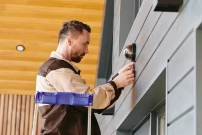 young-man-fixing-alarm-system-on-wall-above-the-do-2025-03-16-11-27-29-utc (2)