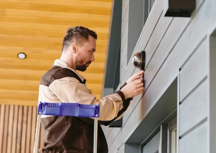 young-man-fixing-alarm-system-on-wall-above-the-do-2025-03-16-11-27-29-utc (2)